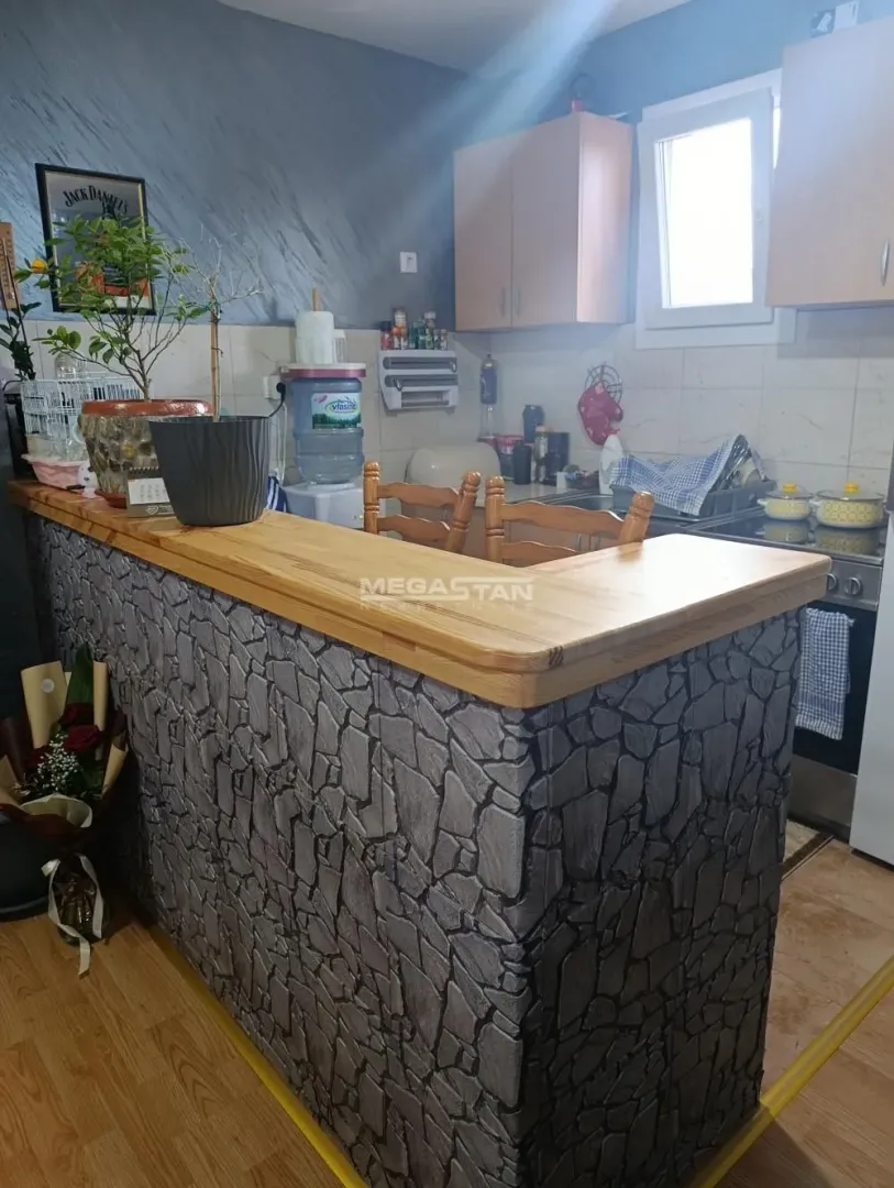 Kitchen with a stone-clad breakfast bar and wooden cabinetry.