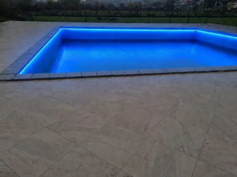 Swimming pool with blue LED lighting in a paved courtyard. - image 3