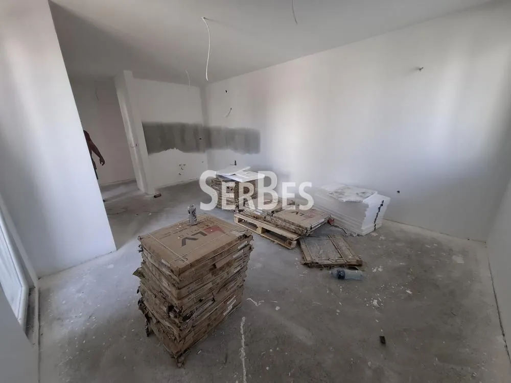 Neuređena prostorija u toku građevinskih radova sa složenim materijalima na podu.