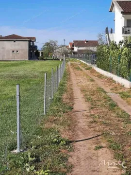Zemljani put pored ograđenog placu u naselju sa kućama. - image 2