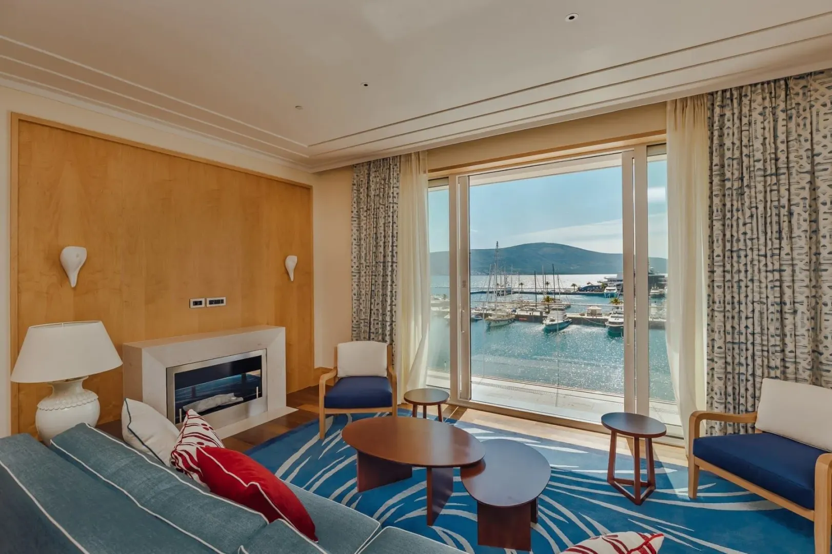 Dnevna soba sa kaminom i velikim prozorom sa pogledom na marinu.
