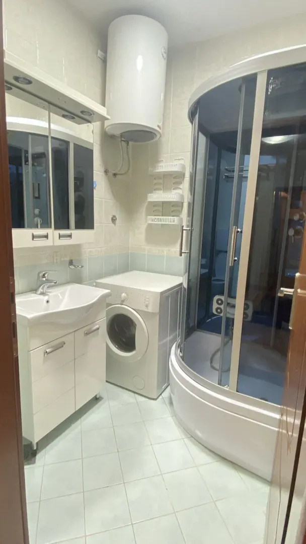 Bathroom with a shower cabin, sink, and washing machine.