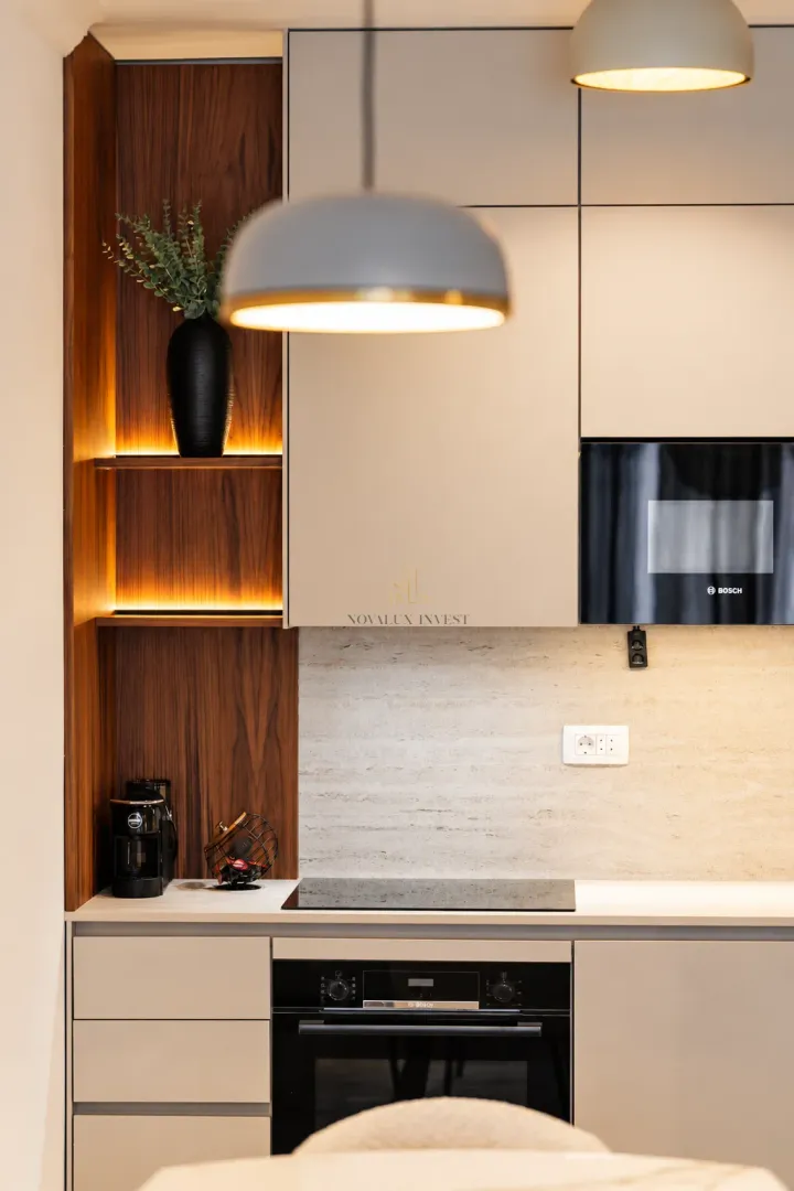 Modern kitchen with built-in appliances and decorative lighting.