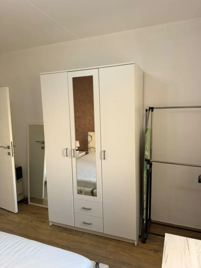 Bedroom with a white wardrobe and a mirror.