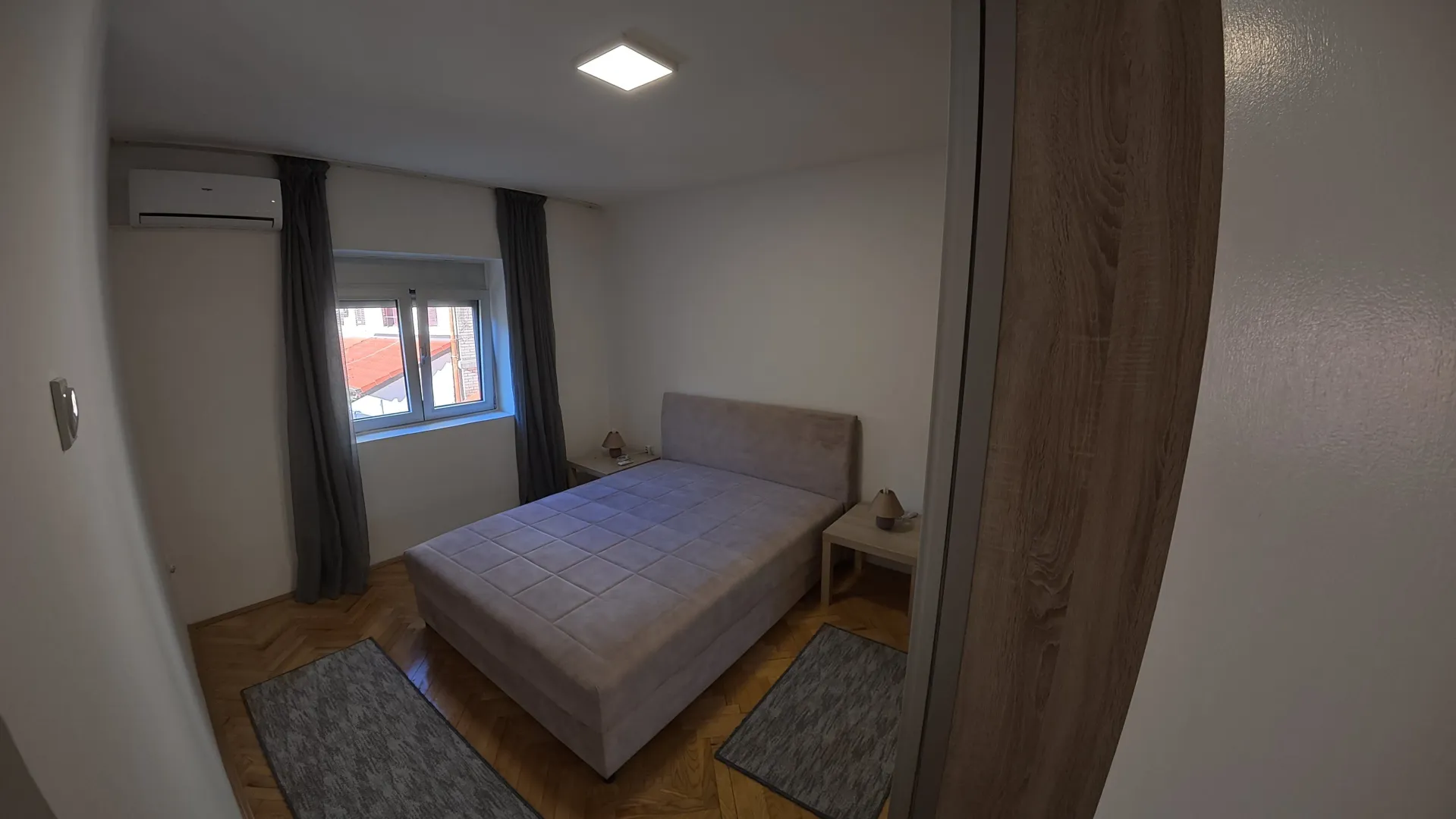 Furnished bedroom with a double bed, bedside tables, and a window.
