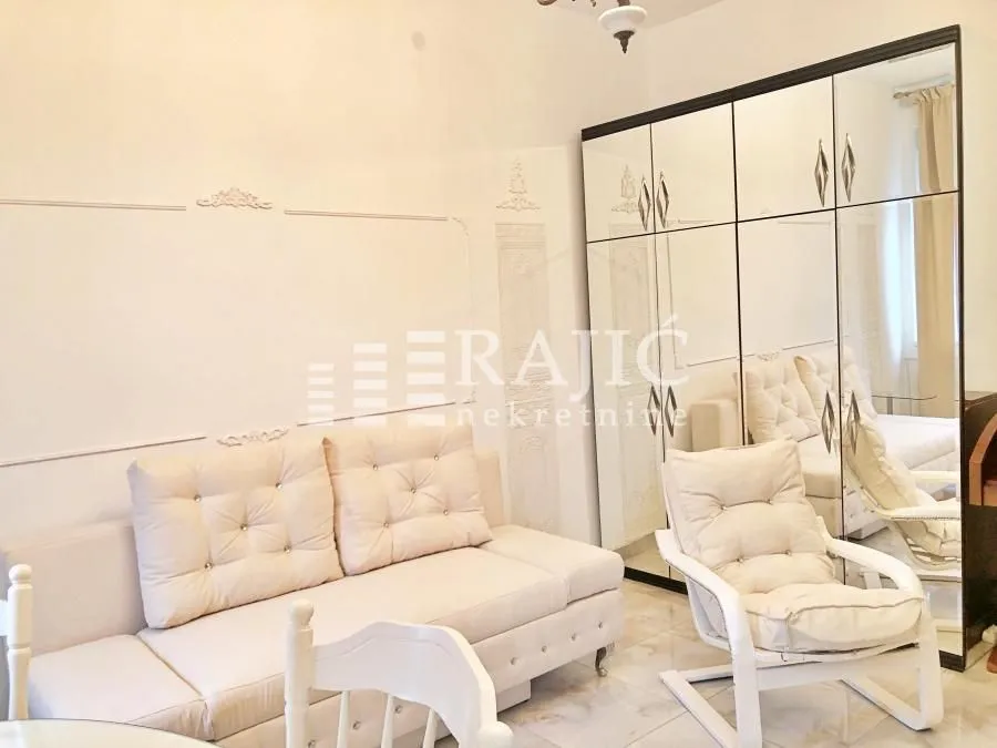 Living room with a beige sofa and a large mirrored wardrobe.