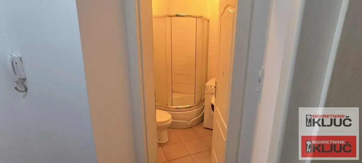 Pogled na kupatilo sa tuš kabinom kroz otvorena vrata.