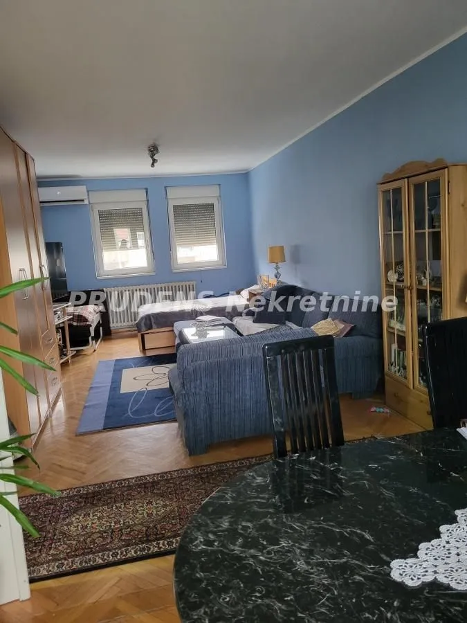 Dnevni boravak sa garniturom za sedenje i trpezarijskim stolom u prvom planu.
