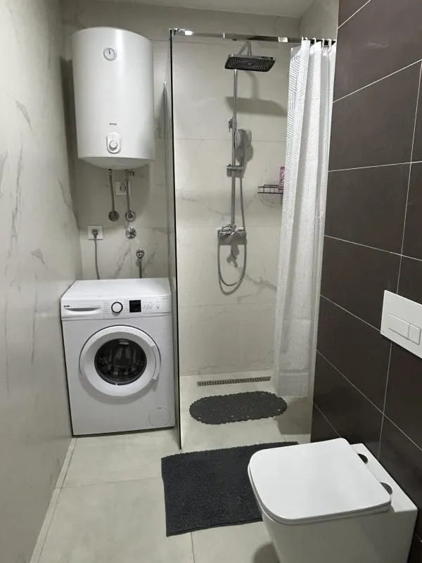 Kupatilo sa tuš kabinom, WC šoljom, veš mašinom i bojlerom.
