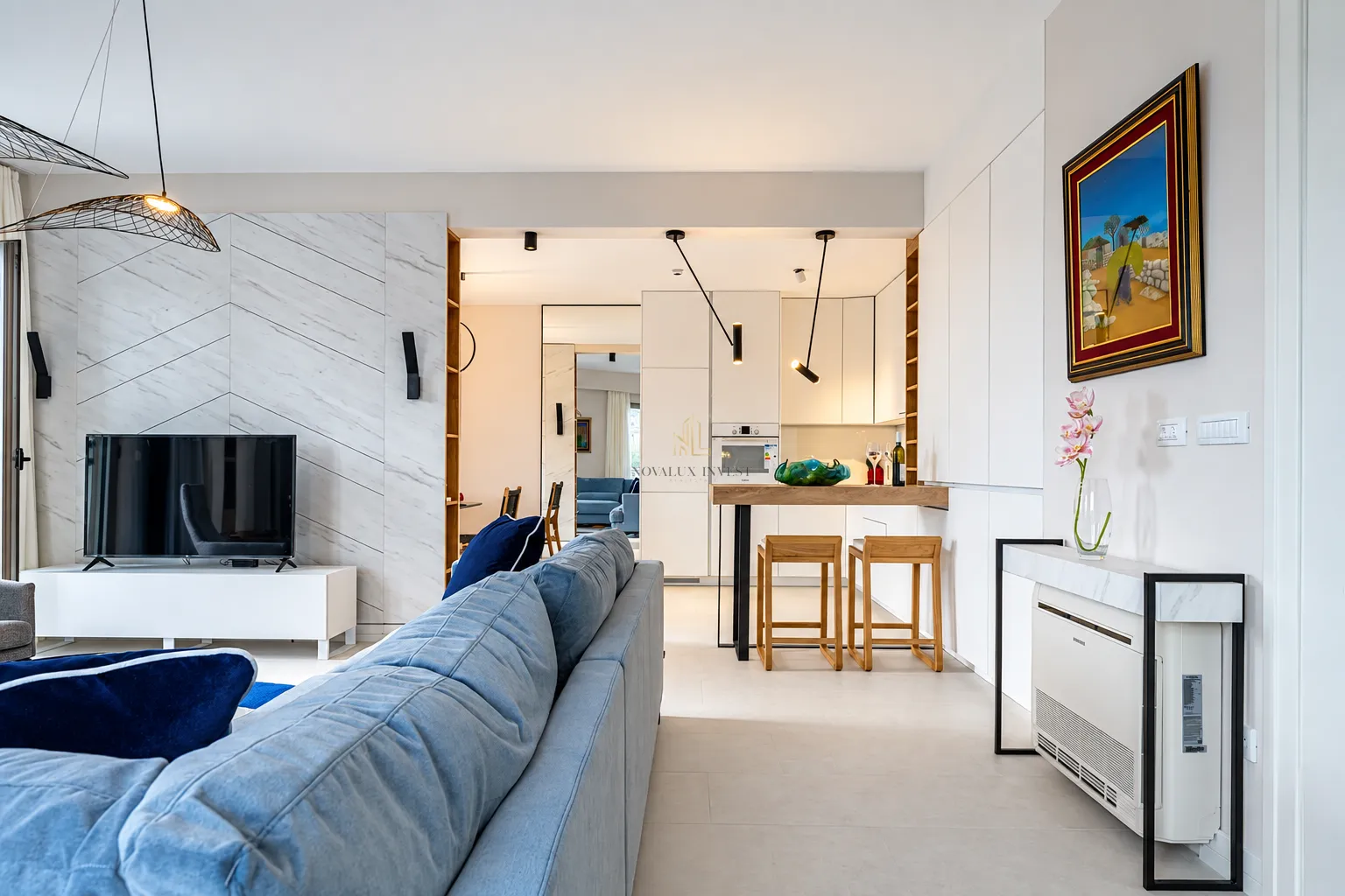 Living room with a comfortable blue sofa and a view towards the kitchen and bar area.