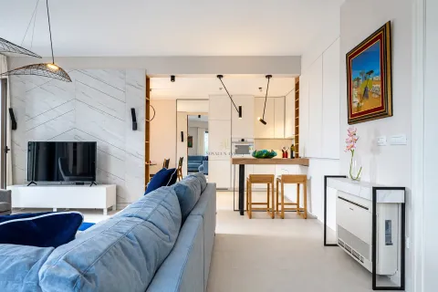 Living room with a comfortable blue sofa and a view towards the kitchen and bar area. - image 4
