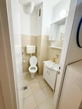 Manje kupatilo sa toaletom, umivaonikom i bijelim ormarićem. - image 7