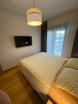 Namještena spavaća soba sa bračnim krevetom, televizorom na zidu i balkonskim vratima. - image 8