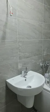 Kupatilo sa sivim pločicama i umivaonikom. - image 2