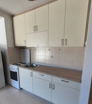 Small kitchen with light cabinets and a stove. - image 3