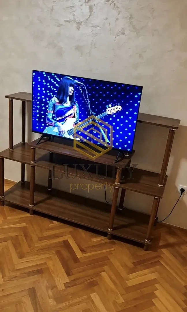 Dnevna soba sa TV komodom i parketom na podu.