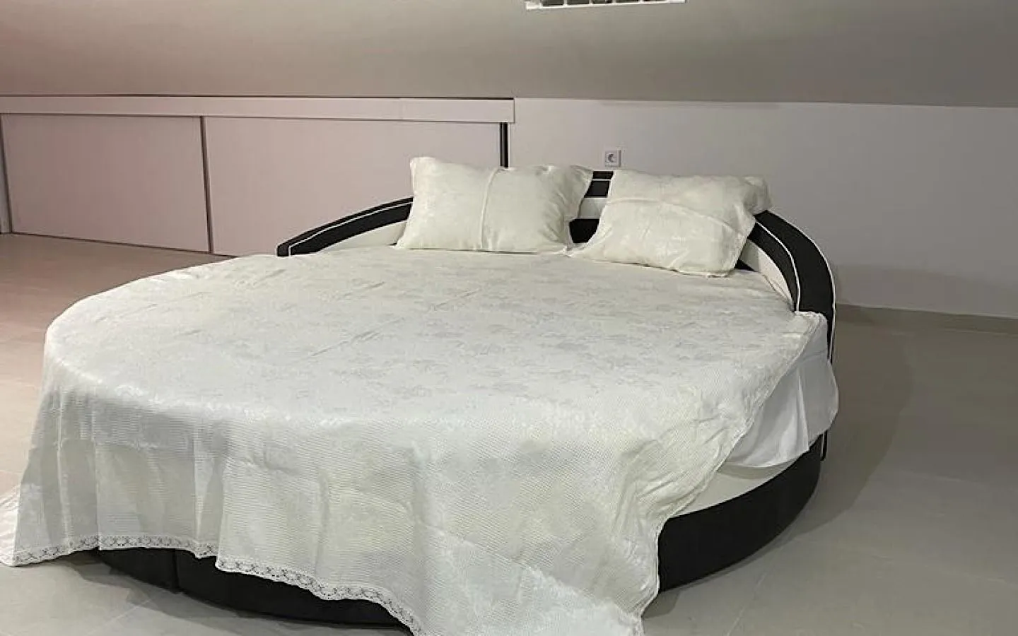 Bedroom with a large round bed and sloped ceiling.