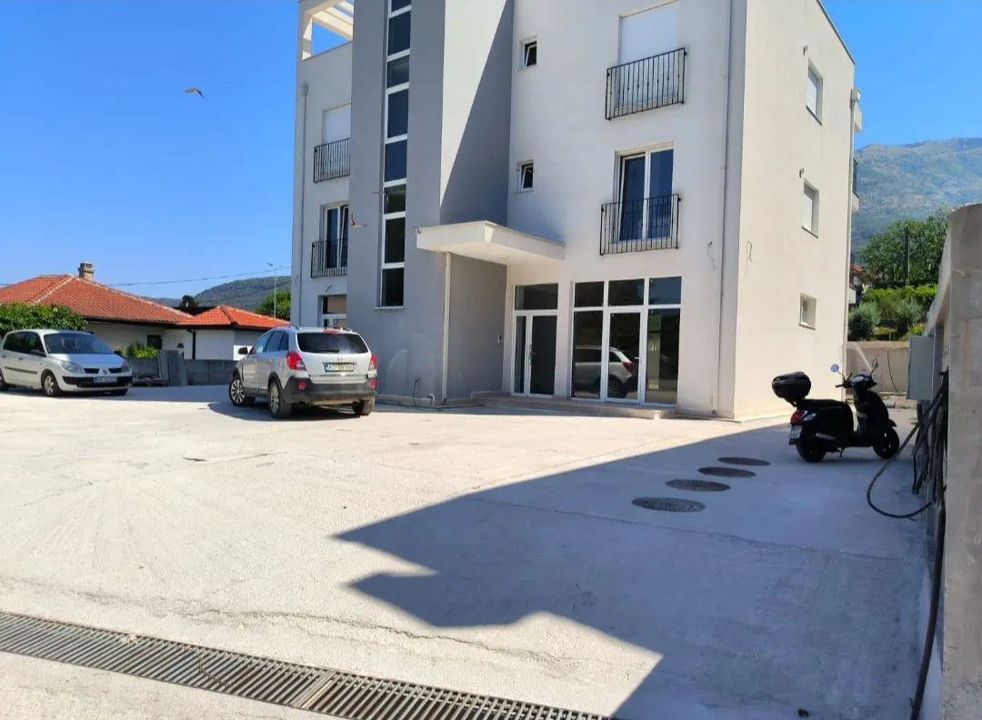 Exterior of a modern residential building with a parking lot and entrance.