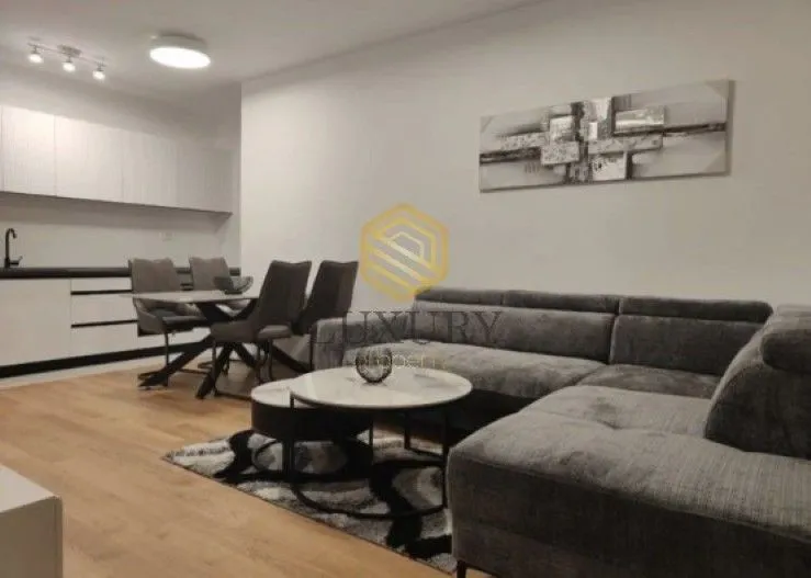 Modern living room with a sofa, dining area, and kitchen.