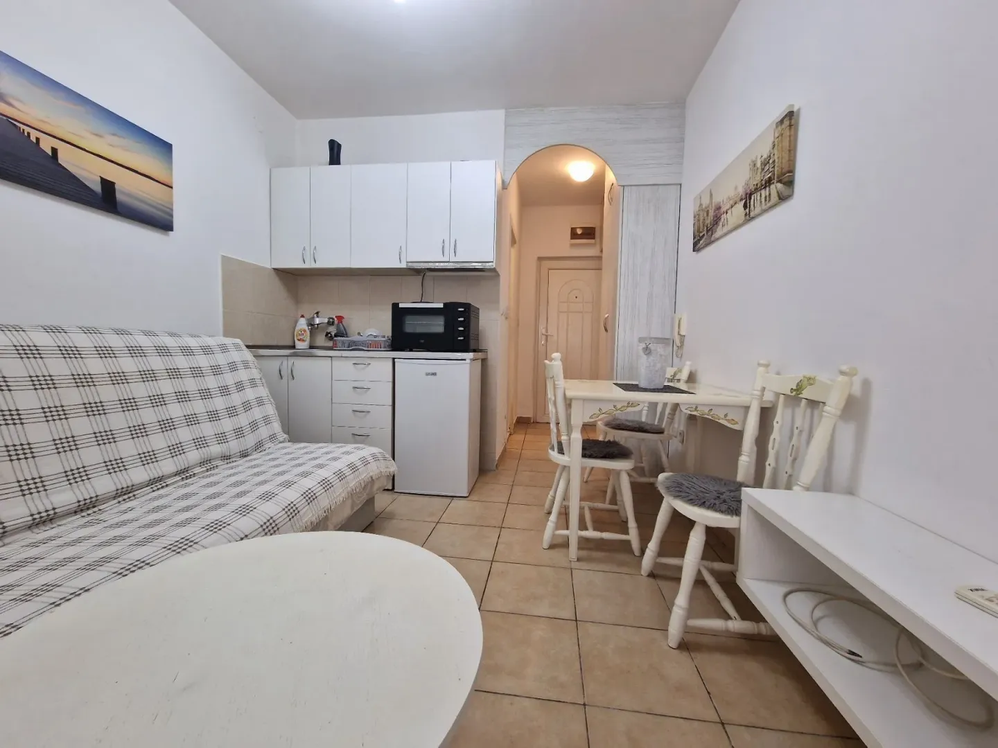 Living room with a sofa, dining table, and a small kitchen area.
