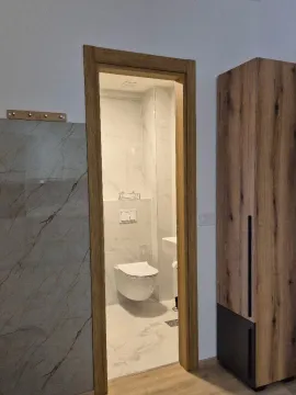 Pogled kroz vrata na uređeno kupatilo sa bijelim pločicama. - image 13