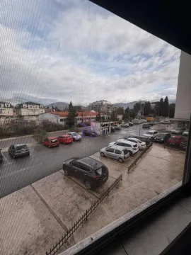 Pogled kroz prozor na parking i okolne zgrade. - image 8