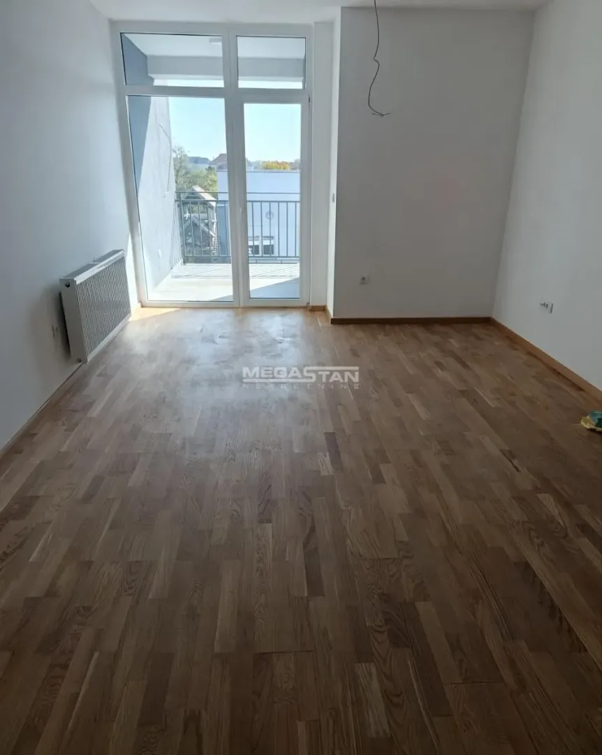 Prazna soba sa parketom i izlazom na terasu.