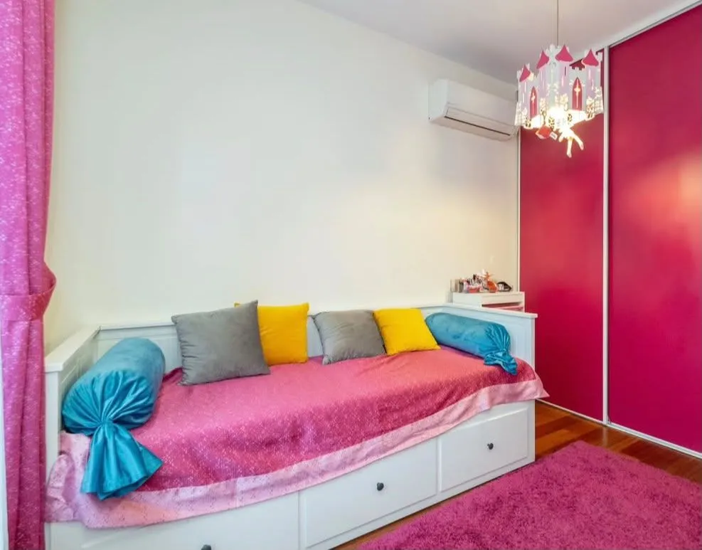 Children's bedroom with a bed, wardrobe, and pink details.