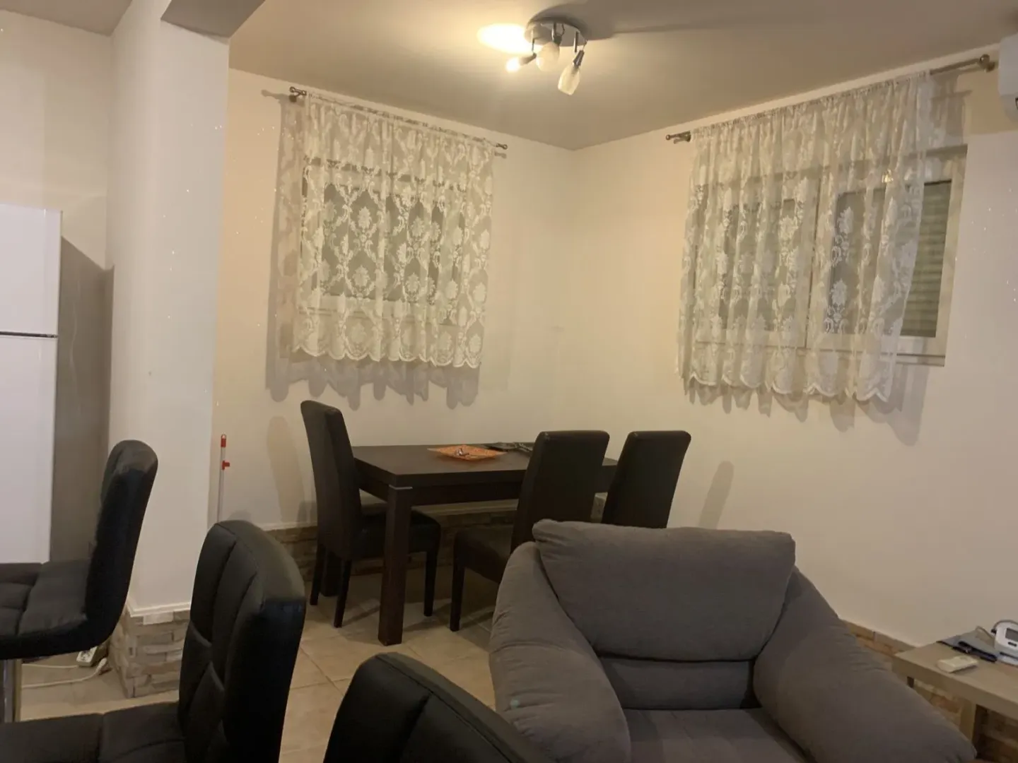 A dining table with chairs and a comfortable armchair in the living room.