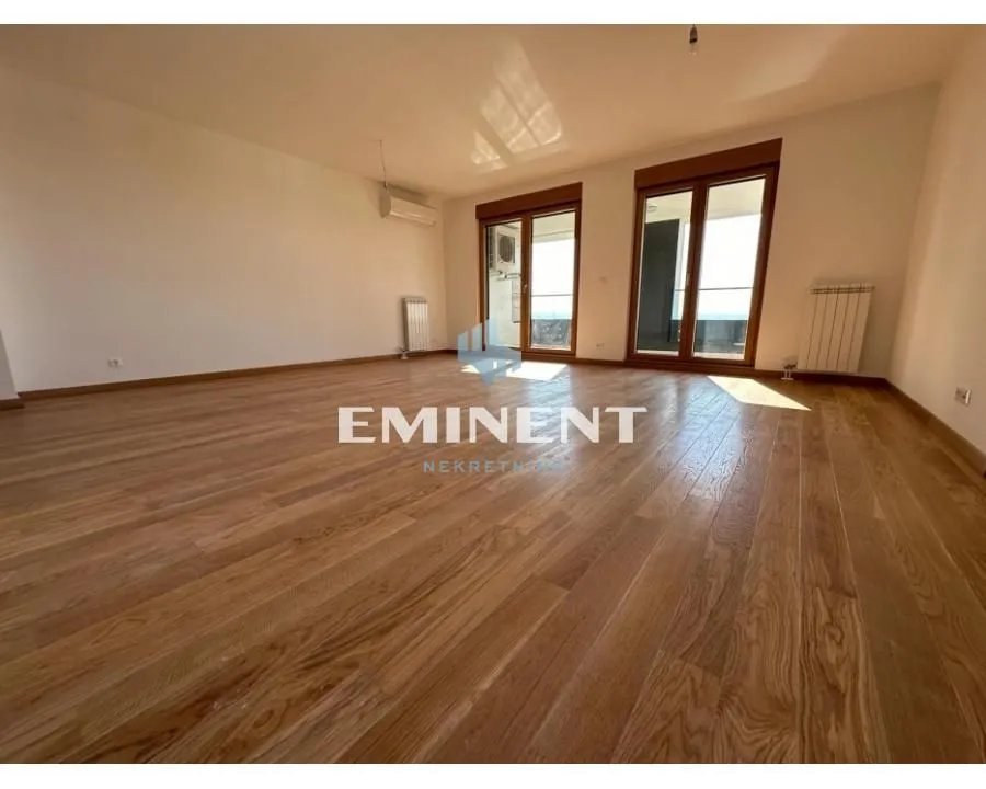 Empty living room with wooden parquet flooring and access to the terrace.