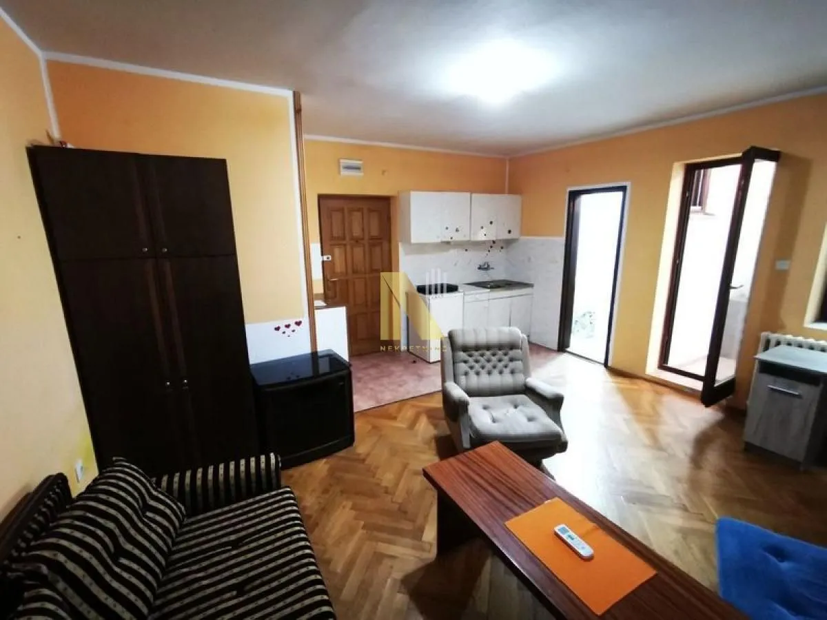 Dnevni boravak sa garniturom i trpezarijskim delom u pozadini.