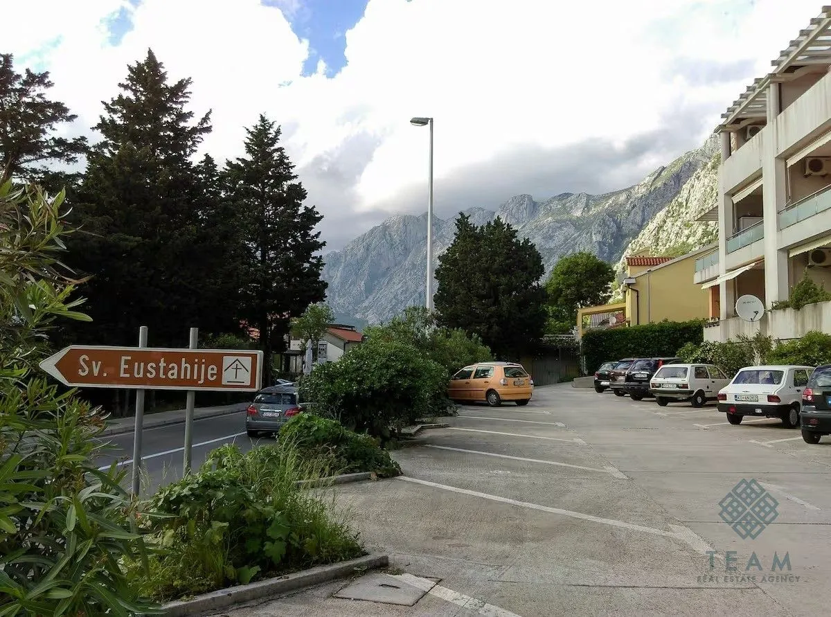 View of the parking lot in front of the building with a road sign and mountain landscape in the background.
