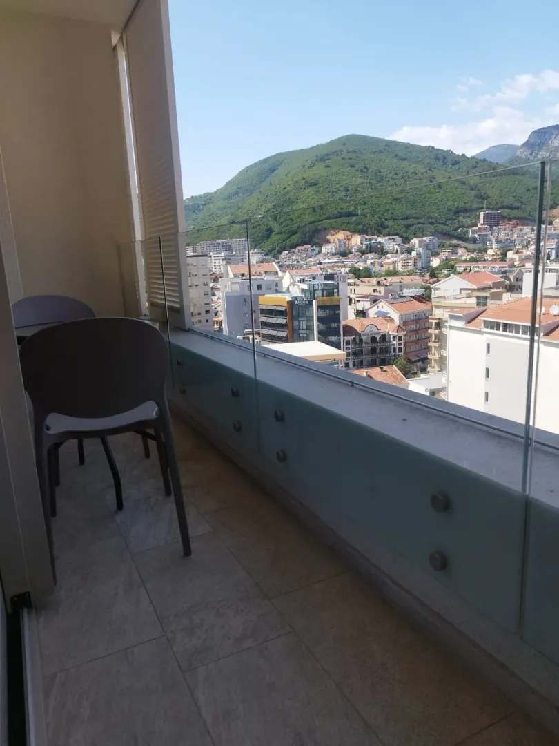 Modern balcony with glass railing and views of the city and mountains.
