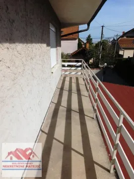 Dugačak spoljni balkon sa belom ogradom i pogledom na okolinu. - image 29