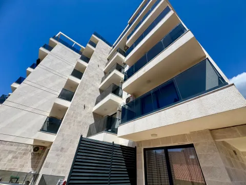Low-angle exterior view of a modern apartment building with balconies and a clear blue sky. - image 13