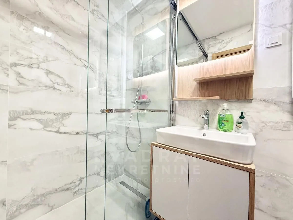 Modern bathroom with a glass-enclosed shower and a vanity unit with a sink.
