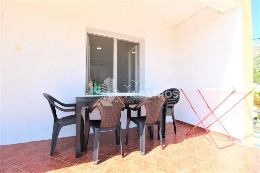 Covered terrace with a table, chairs, and a clothes drying rack.