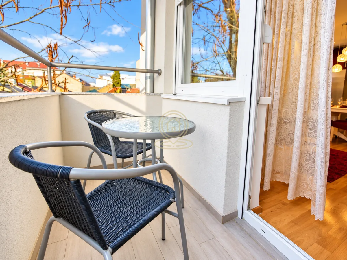 Manji namesten balkon sa stolom i dve stolice.