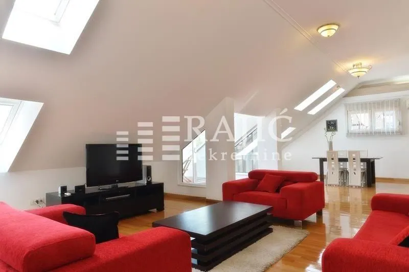 Spacious living room with red sofas and skylight windows in the attic.