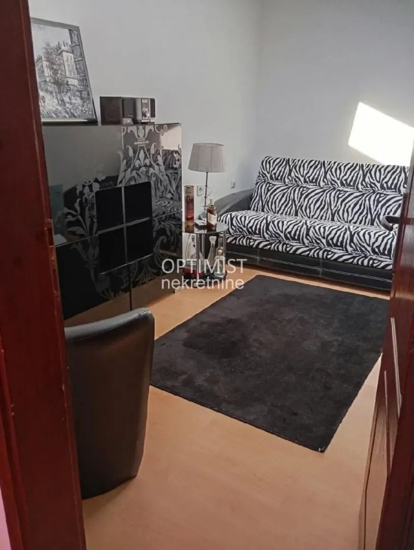 Living room with a patterned sofa and a black rug.