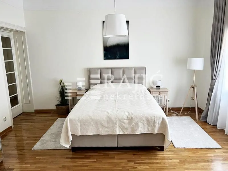 Spacious bedroom with a double bed and wooden flooring.