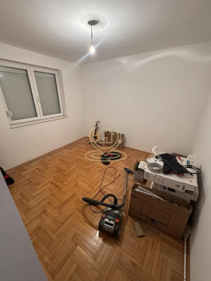 Prazna soba sa parketom i kutijama tokom spremanja.