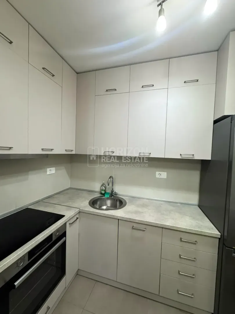 View of a small kitchen with light cabinets and built-in appliances.