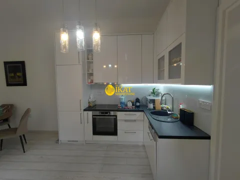 Modern white kitchen with black countertops and built-in appliances. - image 10