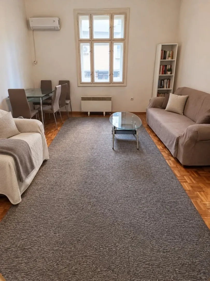 Dnevna soba sa garniturom za sedenje, stočićem i trpezarijskim delom.