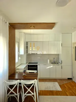 Modern white kitchen with wooden accents and a dining table. - image 3