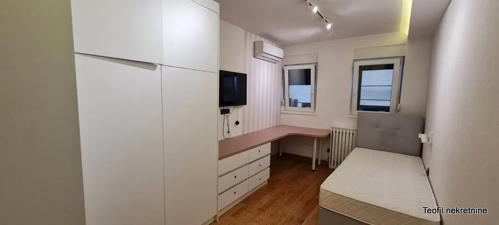 Manja spavaća soba sa krevetom, radnim stolom i velikim ormanom.