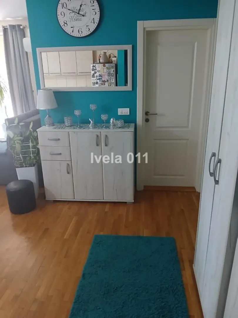 Pogled na deo dnevnog boravka sa komodom, ogledalom i plavim zidom.