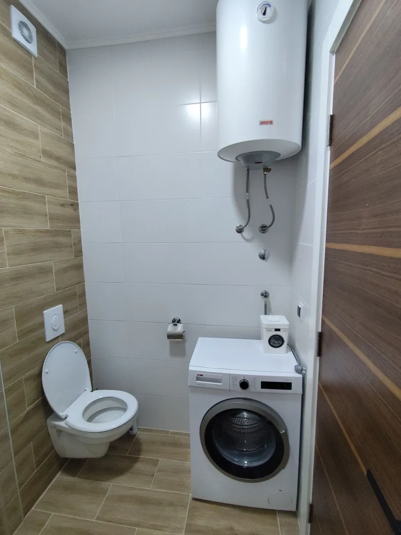 Manje kupatilo sa toaletom, veš mašinom i bojlerom.