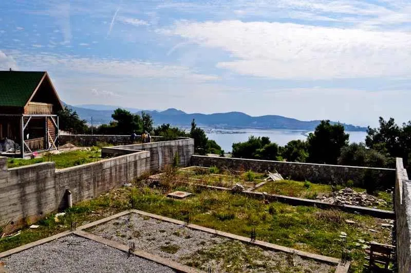 Pogled na plac u izgradnji sa betonskim temeljima i okolnim pejzažom.